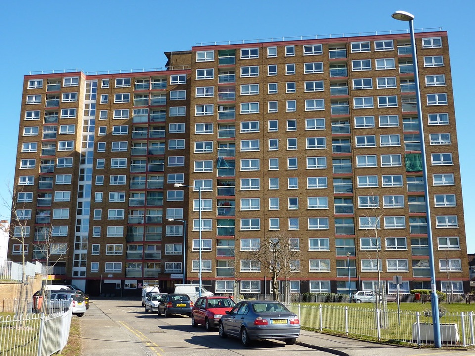 A tall brick block of flats with rows of open balconies, in Bristol